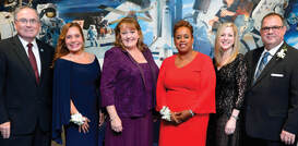 Christy Harper stands with five University of Houston-Clear Lake alumni members. All wear formal dress attire. 
