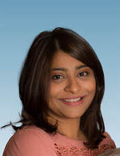 Head shot portrait of Pallavi Banerjee. She has brown hair and is wearing a pink embroidered blouse.